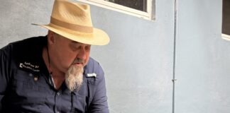 a man sitting on a bench petting a small white dog