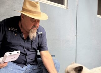 a man sitting on a bench petting a small white dog