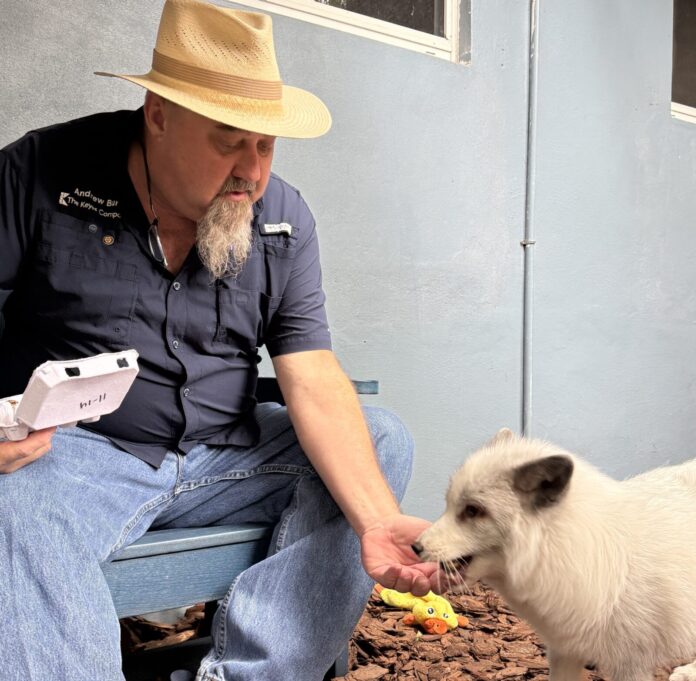 a man sitting on a bench petting a small white dog