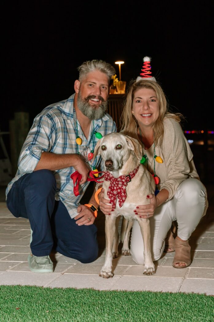a man and a woman pose for a picture with a dog