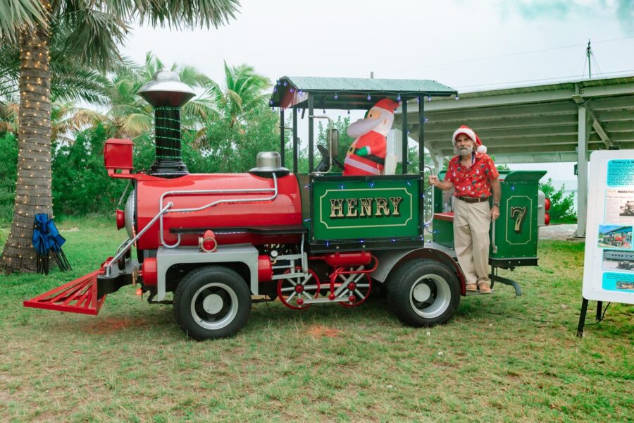 a man standing next to a red and green train