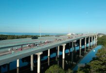 HUNDREDS CONQUER KEY LARGO BRIDGE RUN 5K AND 10K a bridge over a river with people walking on it