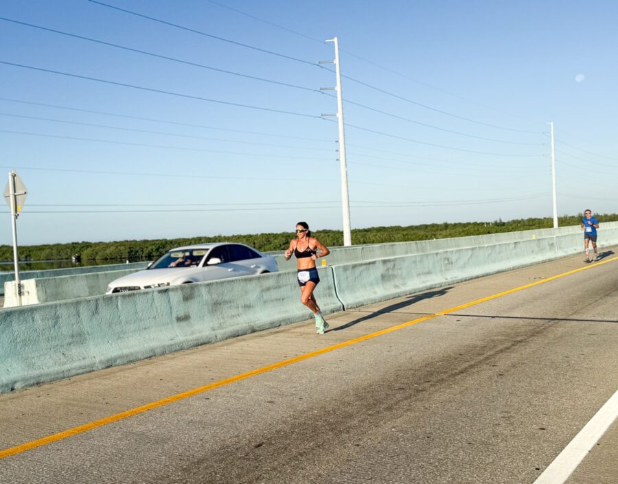 a man running across a bridge next to a car