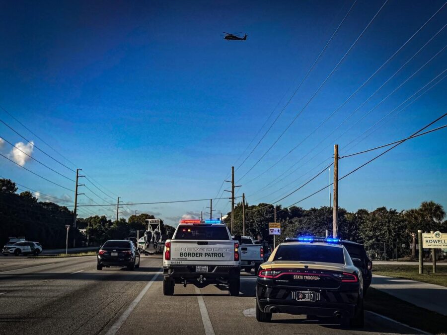 a police car driving down a street next to a helicopter