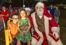 a group of children standing next to a santa clause