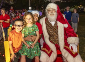 a group of children standing next to a santa clause