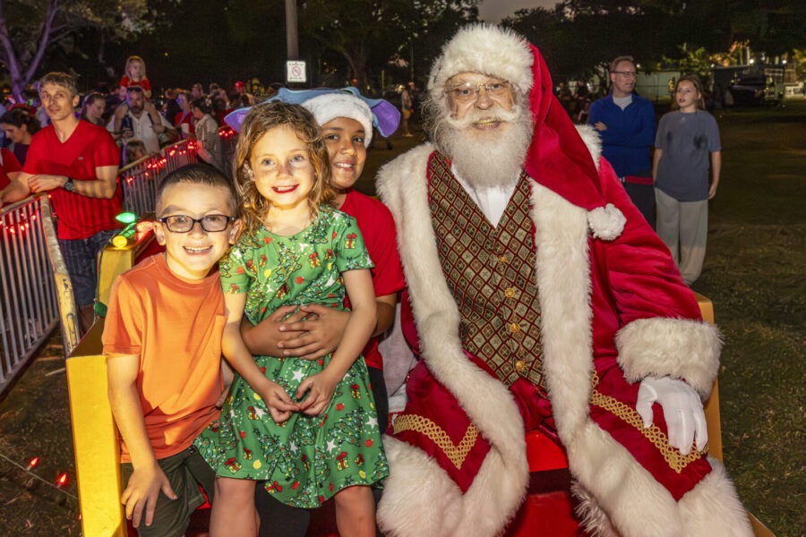 a group of children standing next to a santa clause