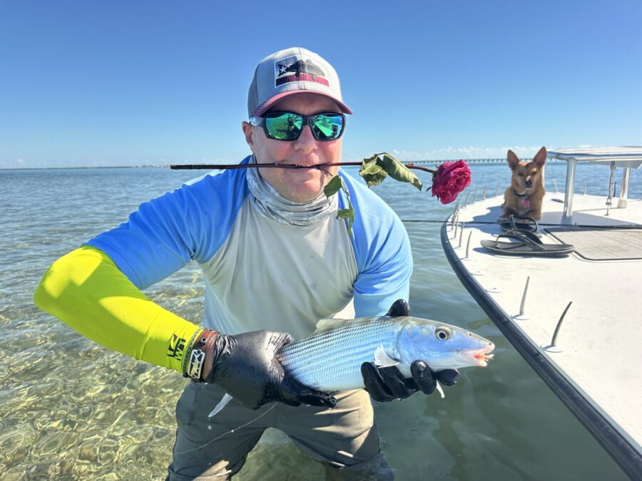 a man holding a fish while standing on a boat