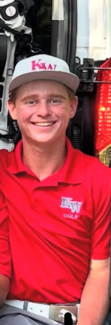 a man in a red shirt and hat sitting in front of a truck