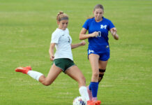 two girls are playing soccer on a field
