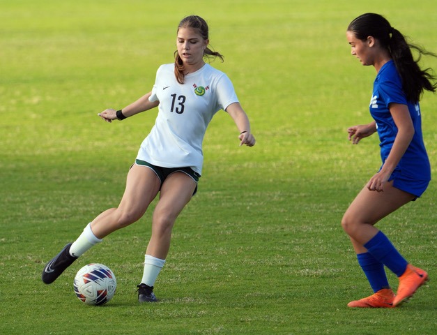 two girls playing soccer on a soccer field