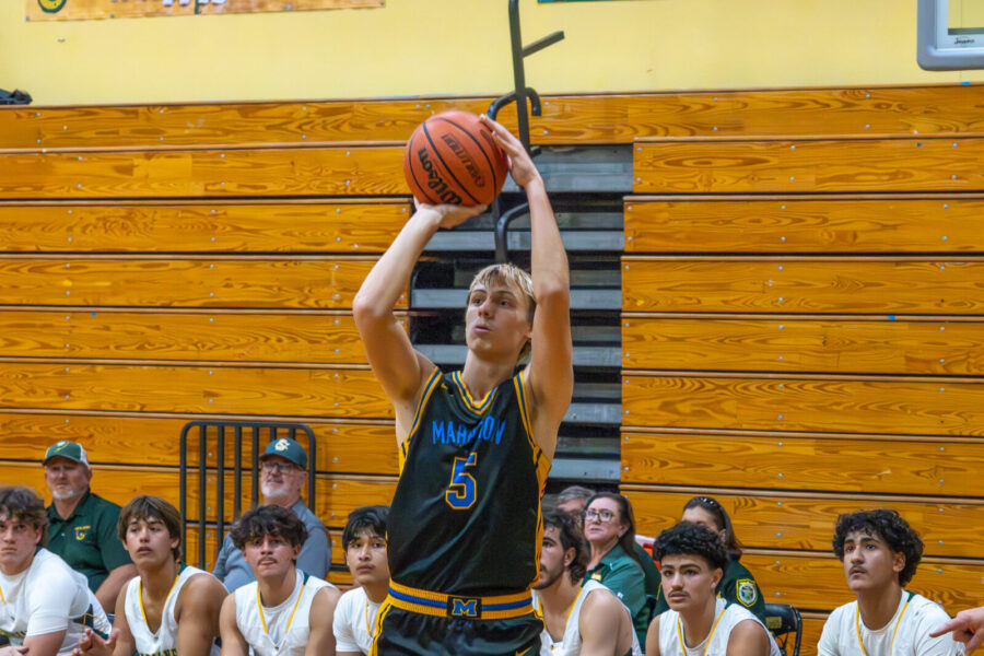 a young man shooting a basketball during a game
