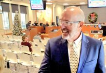 a man in a suit and tie standing in a room full of people