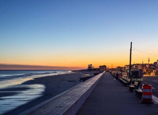 a view of a beach at sunset from a boardwalk