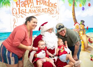 IN PICTURES: ISLAMORADA’S HOLIDAY FEST TRANSFORMS FOUNDERS PARK INTO A MAGICAL WINTER WONDERLAND a group of people posing for a picture with a santa clause
