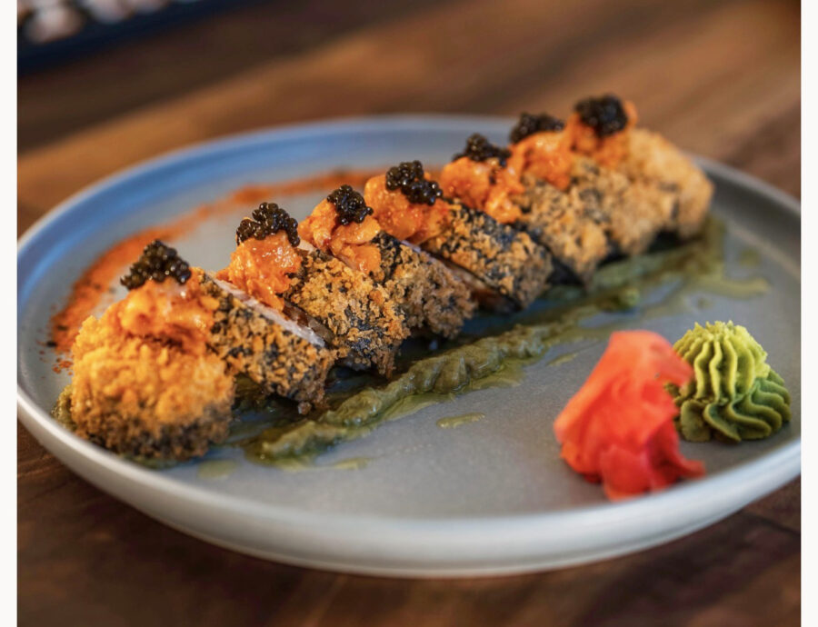 a white plate topped with sushi on top of a wooden table