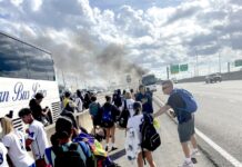 BUS CARRYING MARATHON SOCCER TEAMS CATCHES FIRE; NO PLAYERS WERE HURT a group of people standing on the side of a road