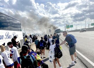 BUS CARRYING MARATHON SOCCER TEAMS CATCHES FIRE; NO PLAYERS WERE HURT a group of people standing on the side of a road