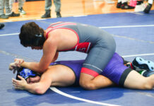 a wrestling player is on the ground with his opponent