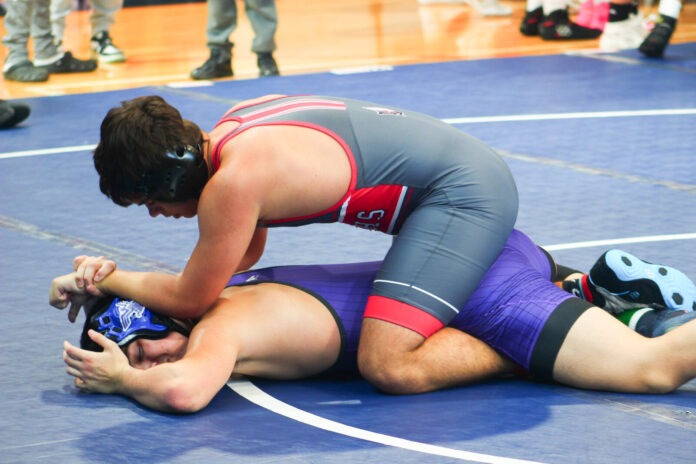 a wrestling player is on the ground with his opponent