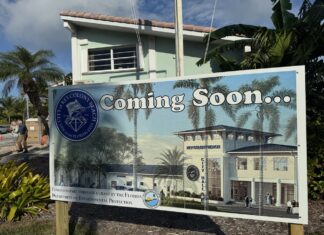 a sign for a building with palm trees in the background