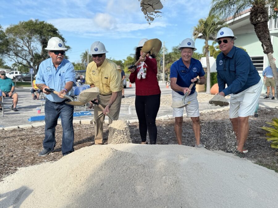 a group of people standing around a pile of sand
