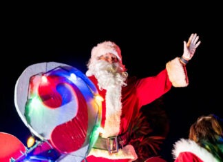 SANTA COMES TO ISLAMORADA THIS SUNDAY; SPECTATORS ENCOURAGED TO SUPPORT LOCAL TOY DRIVE a man dressed as santa claus waves to the crowd