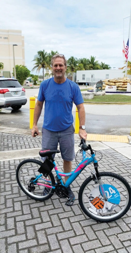 a man standing next to a blue and pink bike