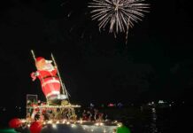 FESTIVE LIGHTED BOATS & FIREWORKS ILLUMINATE BLACKWATER SOUND DEC. 13 a boat with christmas lights on it floating in the water