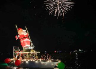 a boat with christmas lights on it floating in the water
