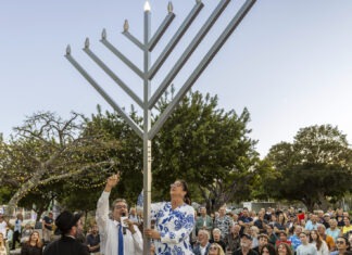 a group of people standing around a menorah