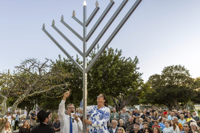 a group of people standing around a menorah