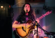 KEY WEST KID HITS GAINESVILLE’S MUSIC SCENE a woman singing into a microphone while playing a guitar