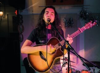 KEY WEST KID HITS GAINESVILLE’S MUSIC SCENE a woman singing into a microphone while playing a guitar