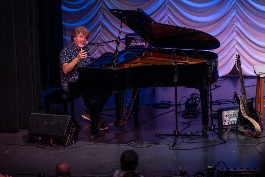 a man standing on a stage next to a piano