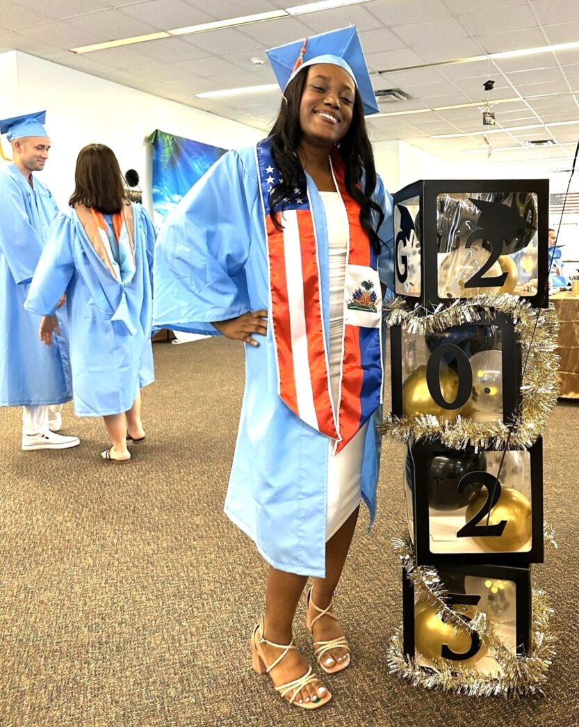 a woman in a graduation gown standing next to a display of shoes