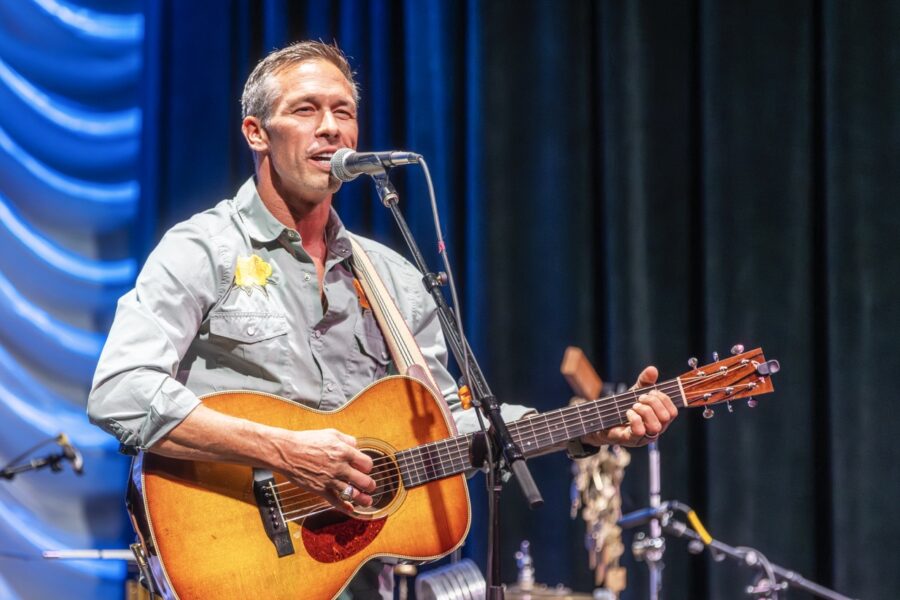 a man playing a guitar while singing into a microphone