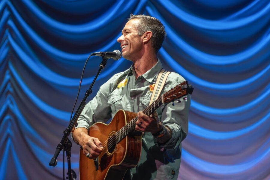 a man playing a guitar and singing into a microphone