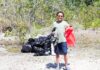SHORELINE CLEANUPS HONOR THE LIFE OF PASCAL WEISBERGER a man standing in the dirt with a red bag