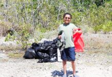 SHORELINE CLEANUPS HONOR THE LIFE OF PASCAL WEISBERGER a man standing in the dirt with a red bag