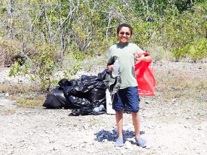 a man standing in the dirt with a red bag