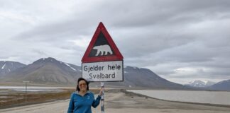 a woman standing next to a sign on the side of a road