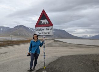 a woman standing next to a sign on the side of a road