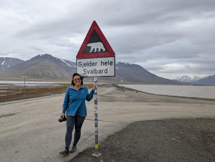 a woman standing next to a sign on the side of a road