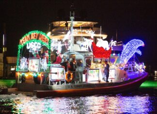 CALLING CAPT. CLAUS: DECK YOUR HULLS & ENTER KEY WEST’S LIGHTED BOAT PARADE a boat decorated with christmas lights on the water