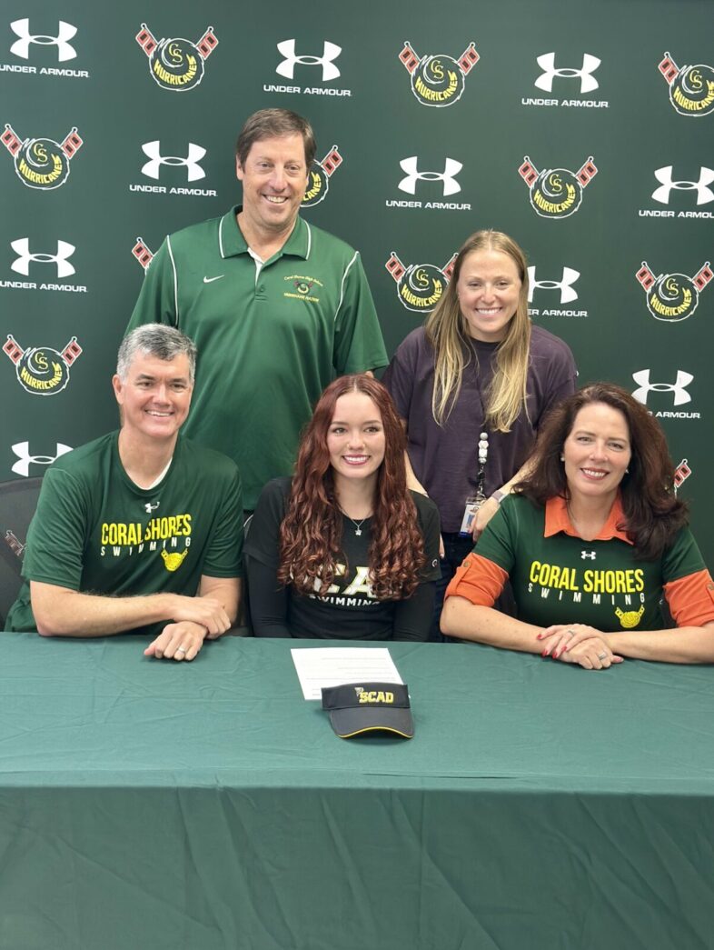 a group of people standing behind a green table