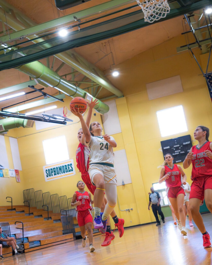 a group of people playing basketball inside of a gym