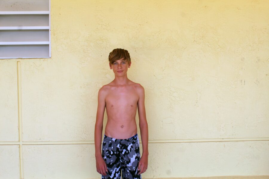 a young boy standing in front of a yellow wall
