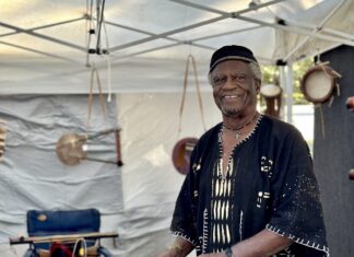 ANNUAL ART UNDER THE OAKS KICKS OFF UPPER KEYS EVENTS SEASON THIS SATURDAY a man playing a musical instrument under a tent