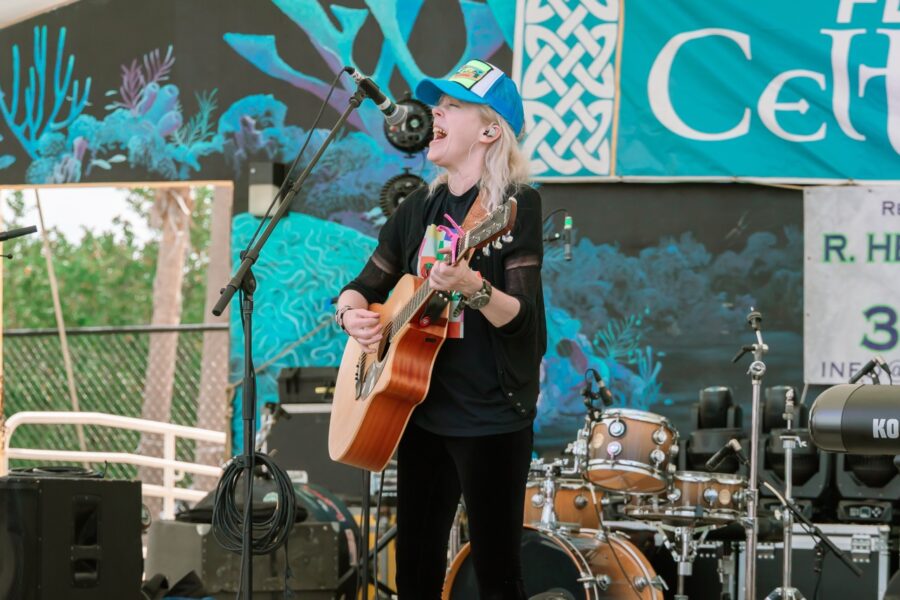 a woman singing into a microphone while holding a guitar
